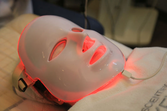 Vrouw gebruikt thuis een LED-lichttherapie toestel voor haar gezicht