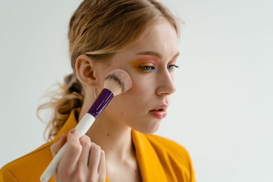 Vrouw brengt blush aan op haar jukbeen met een make-upkwast