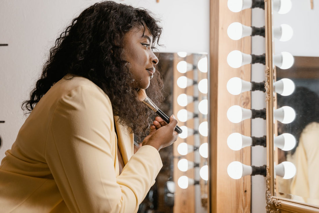 Vrouw brengt make-up aan bij een goed verlichte spiegel
